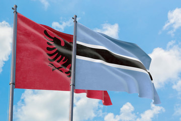 Botswana and Albania flags waving in the wind against white cloudy blue sky together. Diplomacy concept, international relations.