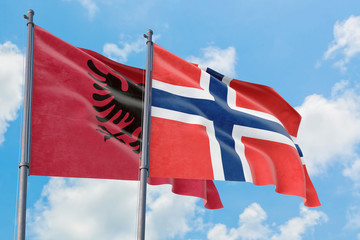 Bouvet Islands and Albania flags waving in the wind against white cloudy blue sky together. Diplomacy concept, international relations.