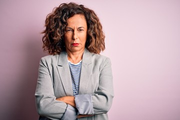 Middle age beautiful businesswoman wearing elegant jacket over isolated pink background skeptic and...