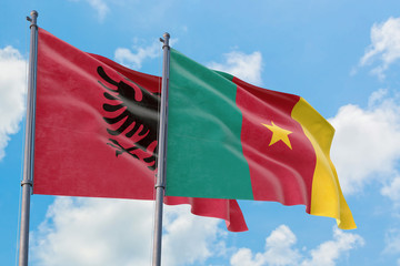 Cameroon and Albania flags waving in the wind against white cloudy blue sky together. Diplomacy concept, international relations.