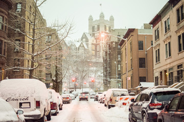 Snow-covered street and cars on a cold and dreary winter's day in Harlem, New York, NY, USA