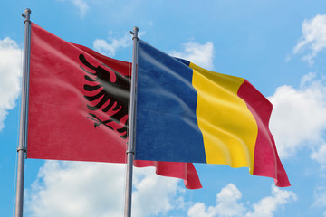 Chad and Albania flags waving in the wind against white cloudy blue sky together. Diplomacy concept, international relations.