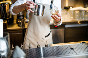 Bartender in apron pouring hot drink in glass