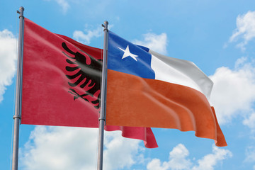Chile and Albania flags waving in the wind against white cloudy blue sky together. Diplomacy concept, international relations.