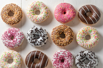 Tasty donuts with colorful decorations on white table