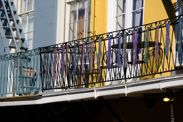 colorful beads hang from a metal balcony in New Orleans' French Quarter