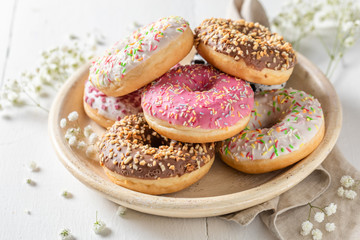 Donuts with various decoration on white plate - obrazy, fototapety, plakaty