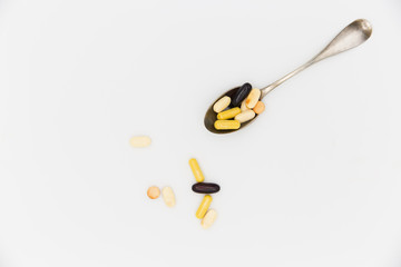 Pills and capsules lie on a spoon. Biologically active food additives.