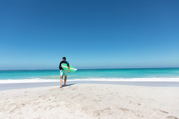 Fototapeta na wymiar Young man walking with surfboard at the beach