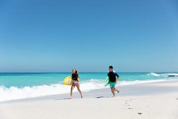 Young couple running with surfboard