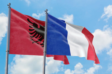 France and Albania flags waving in the wind against white cloudy blue sky together. Diplomacy concept, international relations.