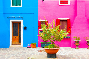 Fototapeta na wymiar Pink and blue painted facades of the houses. Colorful architecture in Burano island, Venice, Italy.