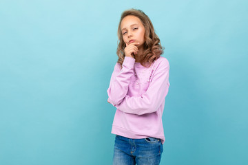 Beautiful schoolgirl in purple blouse thinks about studying isolated on blue background