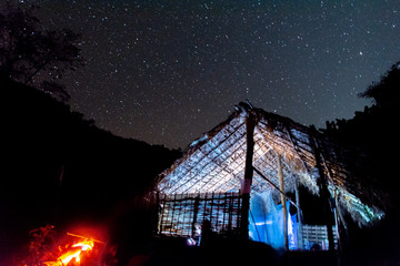 Noche estrellada desde una cabaña y una pequeña hoguera