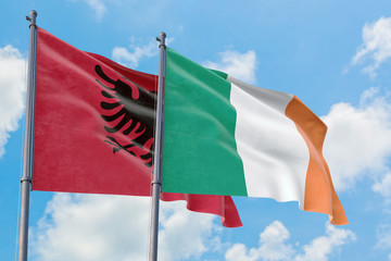 Ireland and Albania flags waving in the wind against white cloudy blue sky together. Diplomacy concept, international relations.