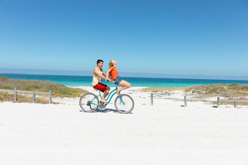 Obraz premium Young couple with bike at the beach