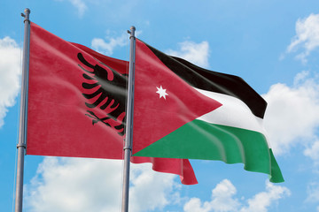 Jordan and Albania flags waving in the wind against white cloudy blue sky together. Diplomacy concept, international relations.