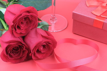 Three red roses lie on a red background with a ribbon