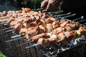 Man Scrolls Skewer with Juicy Pickle Pieces Of Pork or Beef Meat On A Grill.