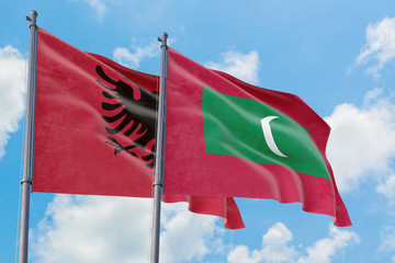 Maldives and Albania flags waving in the wind against white cloudy blue sky together. Diplomacy concept, international relations.