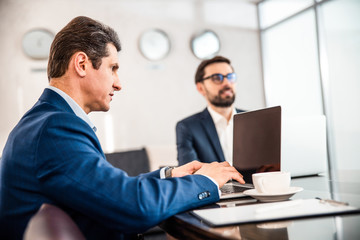 Middle-aged employee sitting next to his dreamy coworker