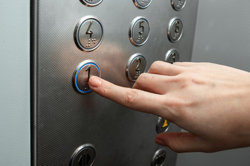 Female hand, finger presses the elevator button. up the career ladder.