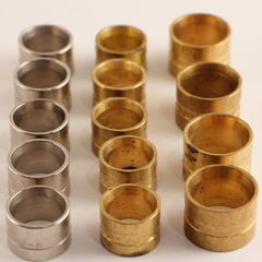 Close up metallic press sleeves rings in perspective on white backdrop, plumbing equipment industrial texture for background