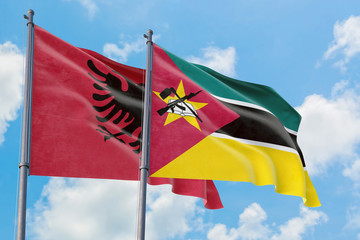 Mozambique and Albania flags waving in the wind against white cloudy blue sky together. Diplomacy concept, international relations.