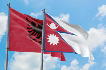 Nepal and Albania flags waving in the wind against white cloudy blue sky together. Diplomacy concept, international relations.