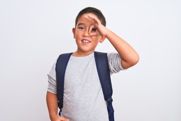 Beautiful student kid boy wearing backpack standing over isolated white background doing ok gesture with hand smiling, eye looking through fingers with happy face.