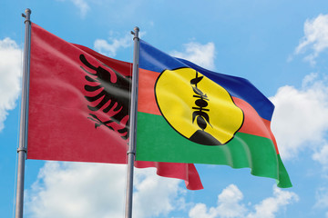 New Caledonia and Albania flags waving in the wind against white cloudy blue sky together. Diplomacy concept, international relations.