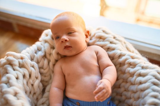 Adorable baby lying down on the floor over blanket at home. Newborn relaxing and resting comfortable