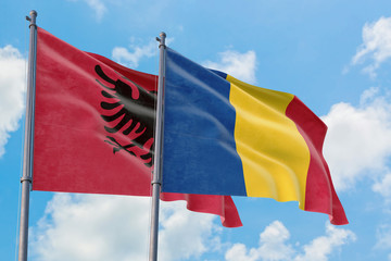 Romania and Albania flags waving in the wind against white cloudy blue sky together. Diplomacy concept, international relations.