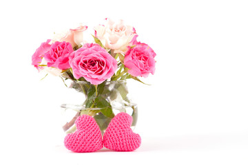Beautiful pink roses in a glass vase on a white background, knitted hearts, DIY. Isolate Concept Valentine's Day, Mother's Day. Holiday gift.