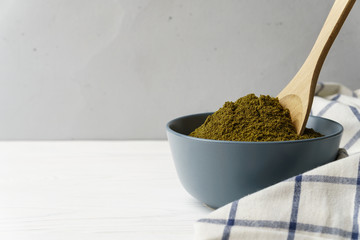 Flour hemp in a gray ceramic bowl with a wooden spoon, cellular textiles on a light concrete surface. Image contains copy space.