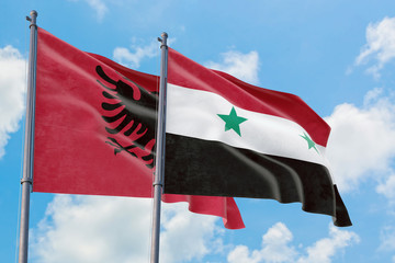 Syria and Albania flags waving in the wind against white cloudy blue sky together. Diplomacy...