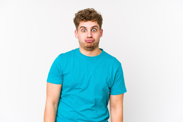 Obraz premium Young blond curly hair caucasian man isolated blows cheeks, has tired expression. Facial expression concept.