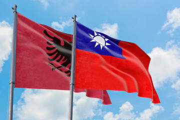 Taiwan and Albania flags waving in the wind against white cloudy blue sky together. Diplomacy concept, international relations.
