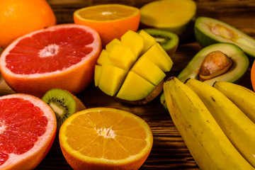 Still life with exotic fruits. Bananas, mango, oranges, avocado, grapefruit and kiwi fruits on wooden table