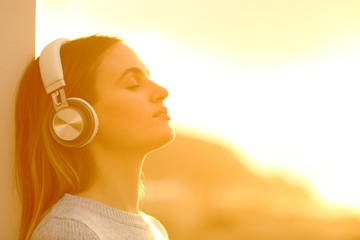 Woman relaxing at sunset listening to music