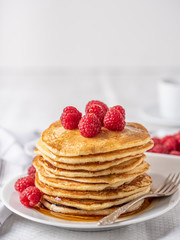 Sweet homemade pancakes with raspberries and blueberries on white plate.