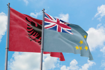 Tuvalu and Albania flags waving in the wind against white cloudy blue sky together. Diplomacy...