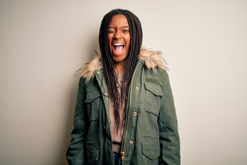 Young african american woman wearing winter parka coat over isolated background winking looking at...