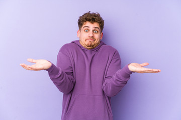 Fototapeta premium Young blond curly hair caucasian man isolated doubting and shrugging shoulders in questioning gesture.