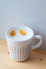 Beautiful white ceramic mug with tasty aromatic coffee and frothed milk stands on light wooden brown table, top view, side view. Free space. Cooking in coffee machine. Coffee eyes, smiley face.