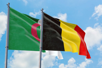 Belgium and Algeria flags waving in the wind against white cloudy blue sky together. Diplomacy concept, international relations.