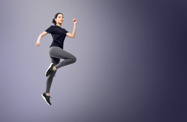 Fototapeta na wymiar Full length portrait of fitness woman in sportswear jumping.