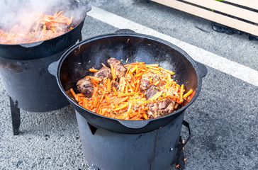 Juicy pieces of meat with carrot cooking in a large cauldron