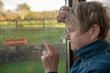 Mature woman looking out of a rainy window