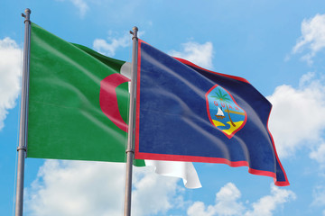 Guam and Algeria flags waving in the wind against white cloudy blue sky together. Diplomacy concept, international relations.
